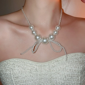 Close-up of elegant pearl necklace with bow knot detail on model neck for luxury look