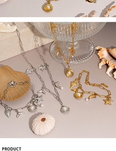 Flat lay of ocean-themed stainless steel necklace and bracelet sets with pearl charms