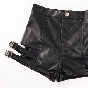 Dettaglio degli shorts a vita alta in ecopelle nera con ritagli laterali e doppie fibbie