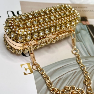 Detailed close-up of golden evening clutch with crystal rhinestones and metal chain