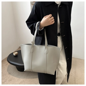 Detail of minimalist grey leather tote bag showing slim handles and spacious design