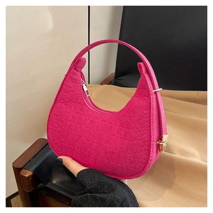 Detailed macro shot of pink crescent felt bag with crocodile texture and gold hardware