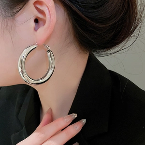 Close-up of a silver chunky hoop earring on model with high-polish mirror finish