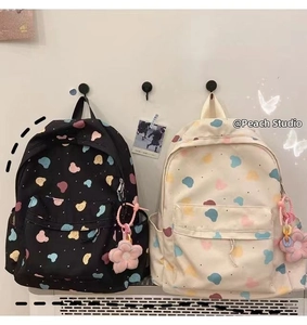 Detail of cute bear print backpacks in black and beige with plush flower charms
