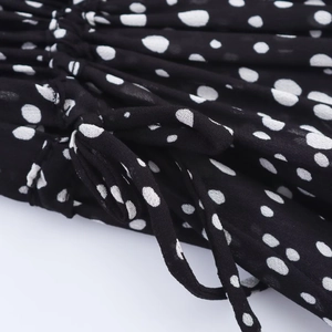 Detail of black polka dot mini dress featuring waist drawstring and ruffled texture