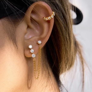 Macro shot of gold tassel earrings with zircon studs and elegant ear cuff chain