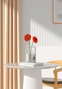 Detail of clear acrylic book-shaped flower vase with artificial flowers and soft shadow