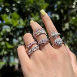 Close-up of S925 silver rings with colorful zircons on a hand with greenery background
