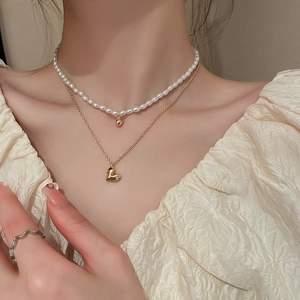 Close-up of double layer necklace featuring a gold heart pendant and white pearls