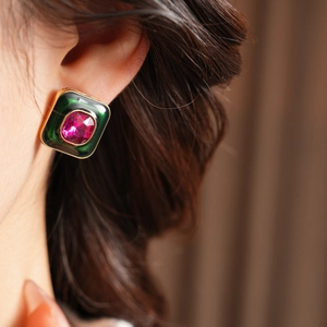 Close-up of vintage square earring with green enamel and pink gemstone on a model