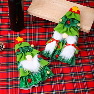 Detail of Christmas tree gnome wine bottle covers on a festive red plaid tablecloth