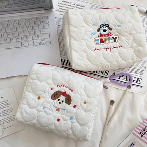 Detail shot of heart-quilted fabric texture and cute puppy embroidery on white pouches