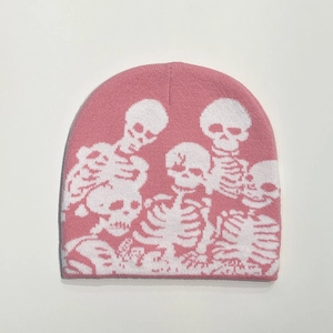 Macro detail of pink knitted beanie featuring white skull patterns and soft ribbed texture