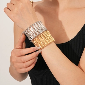 Détail du bracelet large à fils enroulés doré et argenté porté par un mannequin