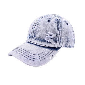 Close-up of distressed ripped details on a light blue washed denim baseball cap