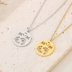 Gold and silver MOM pendant necklaces with baby footprints on a stone display