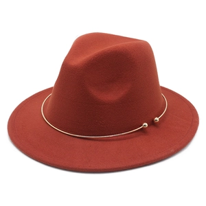 Detail of rust red wool felt fedora featuring a minimalist gold metal ring accent