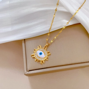 Elegant gold evil eye sun necklace with blue eye and crystals on white silk background