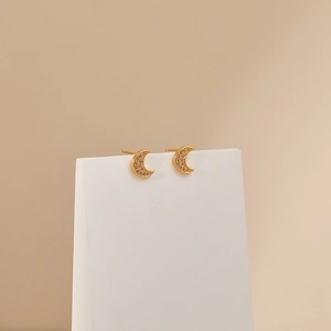 Sparkling gold crescent moon stud earrings with zircon inlay on a minimalist background