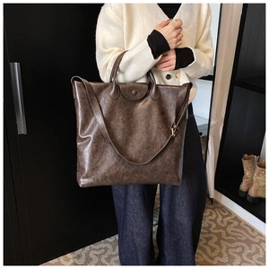 Detail van de vintage bruine leren shopper met gladde textuur en verstelbare schouderriem