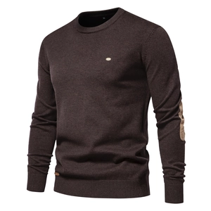 Detail of dark brown crewneck sweater with patch design on sleeve and brand logo badge