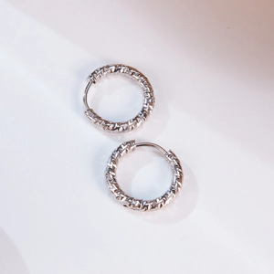 Detail showing minimalist diamond-cut geometric hoop earrings with polished silver finish