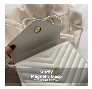 Detail of white quilted crossbody bag showing gold magnetic closure and pearl strap