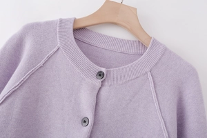 Macro shot of lilac knit cardigan featuring round neck and dark button detail