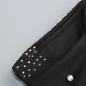 Détails de perles et clous argentés sur une robe noire à épaules dénudées
