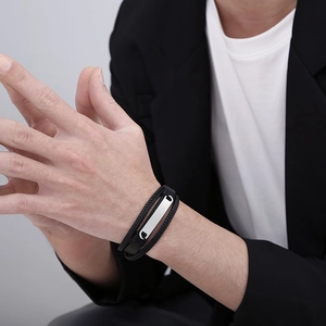 Close-up of a multi-layer black braided leather bracelet with silver metal bar on a wrist