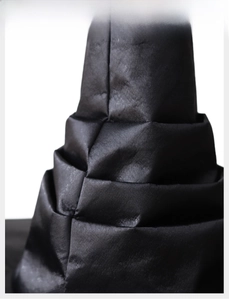 Macro view of black pleated fabric layers on Halloween witch hat with glossy texture