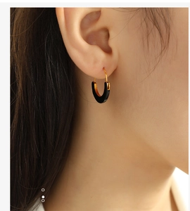 Close-up of a woman wearing U-shaped gold and black enamel earrings for a stylish look