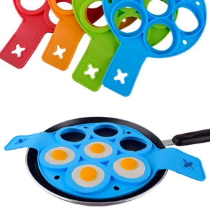 Close-up of 7-hole silicone pancake mold in four colors and in use on a black skillet