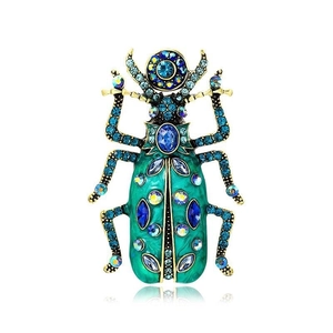Detailed close-up of a beetle brooch featuring turquoise enamel and vibrant blue crystals