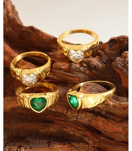 Detailed view of vintage gold rings with emerald and clear heart-shaped gemstones