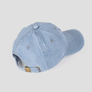 Detail of adjustable metal buckle and vintage denim texture on a light blue baseball cap