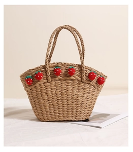Detail of handmade straw basket bag featuring 3D crochet strawberries and woven texture