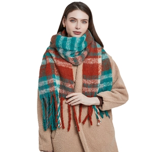 Red and teal plaid scarf with thick tassels made of soft bouclé yarn on white background