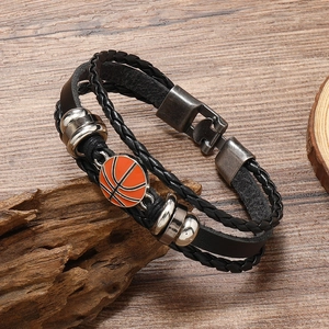 Detail of layered leather bracelet with orange enamel basketball charm on rustic wood