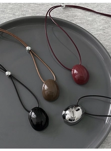 Close-up of pebble shaped pendants in multiple colors with adjustable cord necklaces
