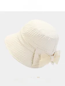 Macro detail of creamy white bucket hat featuring textured dot fabric and organza bow