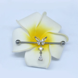 Detail of silver butterfly industrial barbell earring with zircon charms on a frangipani