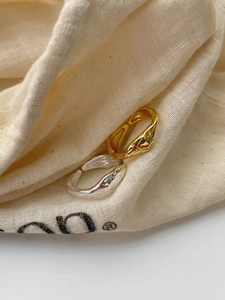 Macro view of adjustable gold and silver lava-textured rings on a linen pouch