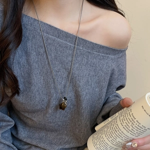 Detail of silver star pendant necklace with tiger eye beads on a gray sweater