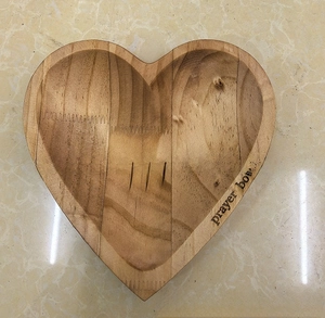 Macro view of heart-shaped wooden prayer bowl featuring engraved crosses and lettering