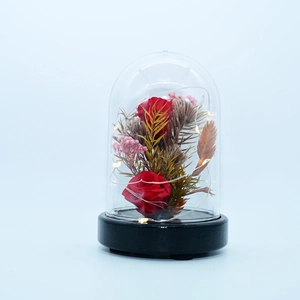 Detail of red preserved roses in a glowing glass dome with a wooden base and LED lights