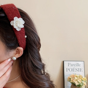Close-up of burgundy flocked headband featuring white camellia flower and pearl accents