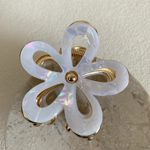 Macro shot of acetic acid flower hair claw with iridescent petals and gold metal frame