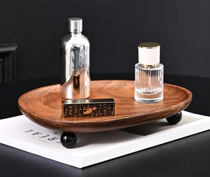 Detail of walnut wooden tray with spherical feet holding perfume bottles and jewelry box