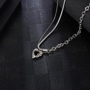 Detail of silver double-layered hip hop necklace with black heart pendant and textured edges